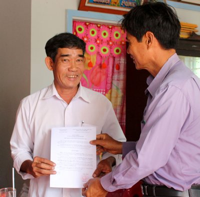 Ông Trần Minh Tâm- Chủ tịch UBND xã trao quyết định bàn giao nhà cho ông Nguyễn Văn Dũng.