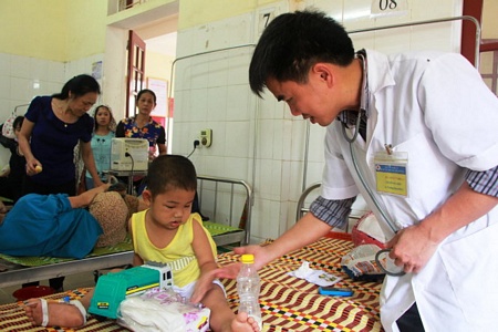 Bác sĩ Nguyễn Bá Thời, trưởng khoa hồi sức cấp cứu, chống độc Bệnh viện Đa khoa huyện Thanh Chương thăm khám cho các bé bị ong rừng đốt - Ảnh: Doãn Hòa