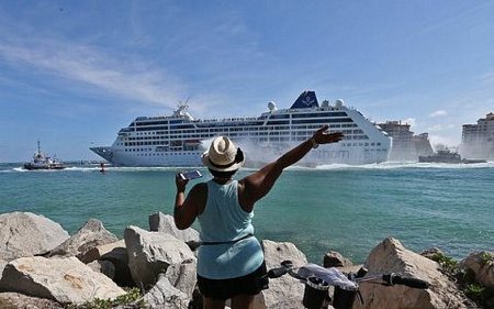 Một phụ nữ Cuba vẫy tay khi tàu Adonia đi qua. Ảnh AP