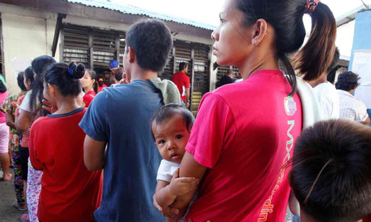 Một phụ nữ bế con tới địa điểm bỏ phiếu ở TP Davao sáng 9-5. Ảnh: REUTERS
