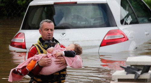 Một người lính cứu hộ đang đưa một em bé ra khỏi vùng ngập lụt. Bức ảnh được chụp khi người này đang đi ở nơi có nước cao quá thắt lưng.