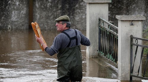 Một cư dân đang lội nước mang bánh mì tới nhà cho mẹ ở quận Montargis, tỉnh lị Orleans do nước đã ngập cao quanh căn nhà của bà.  Description: http://streaming1.danviet.vn/images/2014/share-fb.gif