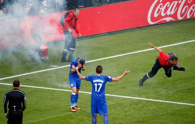Nhân viên cứu hoả và cầu thủ Croatia hoảng hồn khi một quả pháo ném xuống ngay sát chỗ họ đứng.