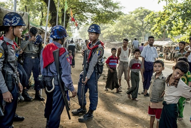 Cảnh sát Myanmar đứng cạnh những người Hồi giáo Rohingya. (Nguồn: New York Times)