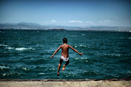 Một cậu bé tị nạn nhảy xuống tắm biển tại Skaramangas, Athens, Hy Lạp. (Nguồn: Sputnik)