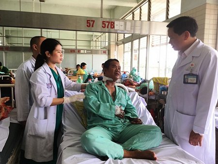 Bác sĩ Hoàng Bá Dũng và Dương Thị Thanh Mai hỏi thăm bệnh nhân sau ca mổ lấy đầu đạn (ảnh K.Q)