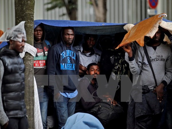 Người di cư chờ để chuyển tới trung tâm lưu trú mới sau khi cảnh sát tháo dỡ khu lán trại phía Bắc Paris. (Nguồn: EPA/TTXVN)