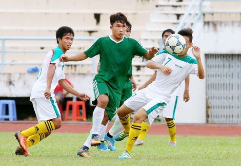 Huy Tín (14, XSKT Cần Thơ- áo xanh) đi bóng trước các cầu thủ Vĩnh Long.