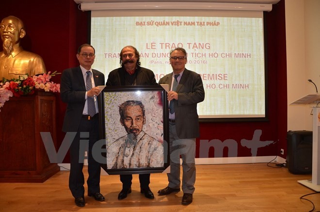 Nghệ sỹ Mustapha Boutadjine (giữa) cùng nhà sử học Alain Ruscio (phải) trao tặng cho Đại sứ Việt Nam tại Pháp Nguyễn Ngọc Sơn bức tranh chân dung Chủ tịch Hồ Chí Minh. (Ảnh: Bích Hà/Vietnam+)