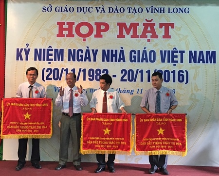 Phó Bí thư Thường trực Tỉnh ủy- Trương Văn Sáu trao cờ thi đua xuất sắc cho Hiệu trưởng Đặng Hoàng Dũng- đại diện Ban Giám hiệu Trường THPT Vĩnh Long (bên trái).