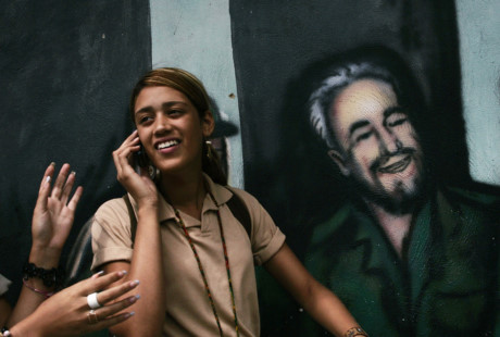 Nữ sinh Cuba đứng bên cạnh bức họa graffiti Fidel Castro ở Caracas. (Nguồn: RT)