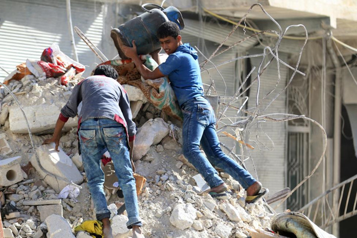 Hai thanh niên cố tìm kiếm chút đồ đạc còn sót lại sau một trận không kích ở khu vực Al-Qaterji, lân cận Aleppo, Syria.