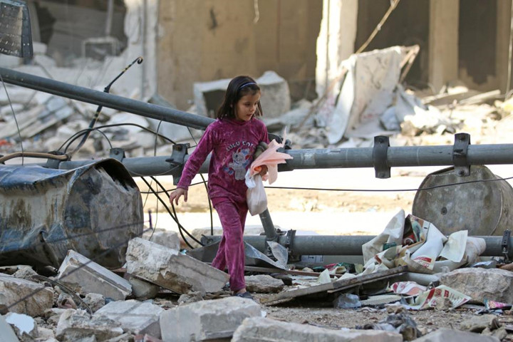 Cô bé bước đi qua những đống đổ nát ở Al-Shaar, gần Aleppo