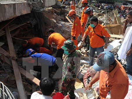 Lực lượng cứu hộ Indonesia tìm kiếm các nạn nhân còn mắc kẹt trong đống đổ nát sau trận động đất tại tỉnh Aceh ngày 7/12. (Ảnh: AFP/TTXVN)