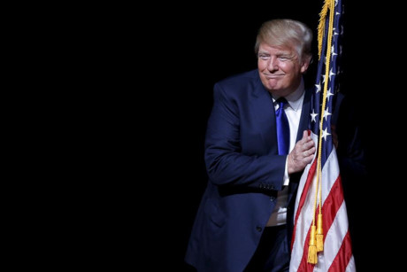 Donald Trump ôm quốc kỳ Mỹ trong buổi vận động tranh cử ở Derry, New Hampshire.