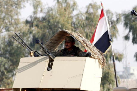 Một quân nhân Iraq đứng trên xe quân sự.