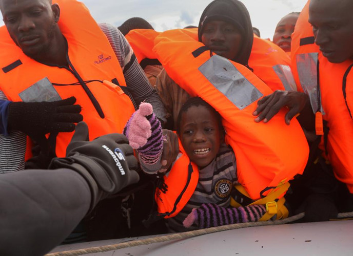 Vẻ mặt hoảng sợ của một đứa trẻ trên chiếc thuyền cao su dù đã được lực lượng cứu hộ phân phát áo phao.
