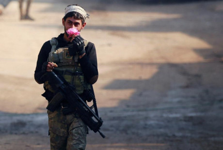 Một thành viên lực lượng phản ứng nhanh của Iraq một tay vẫn giữ súng, một tay cầm bông hồng trên đường đi tuần.