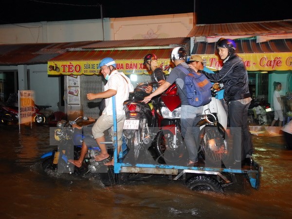 Xe ba gác máy vận chuyển xe máy của người dân qua điểm ngập sâu do triều cường tại TP.HCM. (Ảnh: Mạnh Linh/TTXVN)