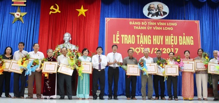 Bí thư Thành ủy- Hồ Văn Huân và Phó Bí thư Thành ủy- Nguyễn Văn Dũng trao Huy hiệu Đảng cho đảng viên 45 tuổi Đảng.