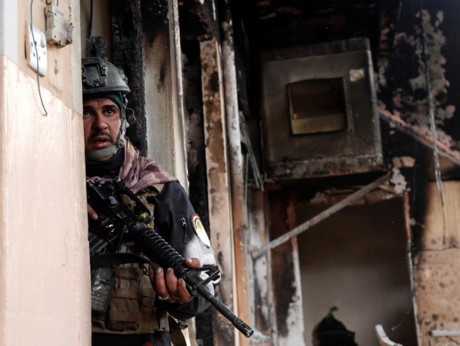 Một binh sĩ Iraq làm nhiệm vụ cảnh giới bên ngoài một ngôi nhà đang bị lục soát. Ảnh: Reuters