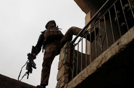 Một binh sĩ Iraq leo từ tòa nhà này sang tòa nhà khác để thực hiện việc lục soát. Ảnh: Reuters