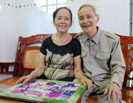 Ông Vĩ và bà Kim Anh cùng xem lại ảnh kỷ niệm gia đình.