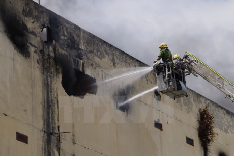 Lực lượng cứu hỏa nỗ lực phun nước dập lửa bên trong nhà xưởng. (Ảnh: Thanh Liêm/TTXVN)