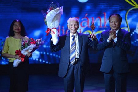 Phó Bí thư thường trực Thành ủy TP.HCM Tất Thành Cang tặng hoa cho NSND Nguyễn Khắc Lợi.