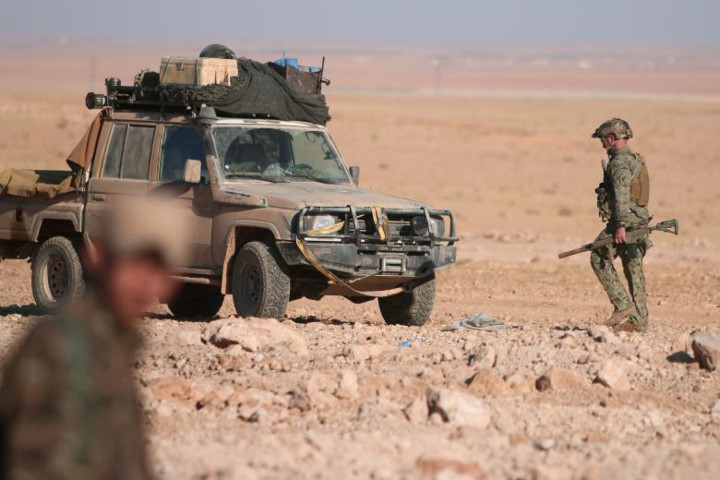 Một binh sỹ Mỹ cùng với vũ khí trên tay đứng gần một chiếc xe quân sự ở phía bắc thành phố Raqqa, Syria.