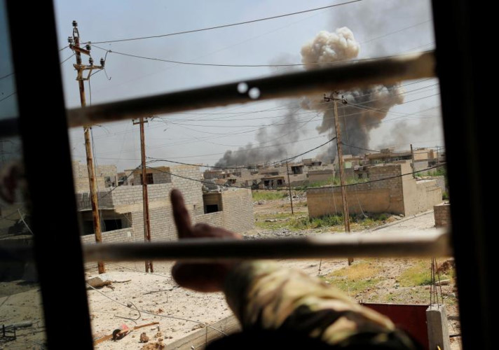 Một binh sĩ Iraq chỉ tay về phía vừa diễn ra các cuộc không kích.