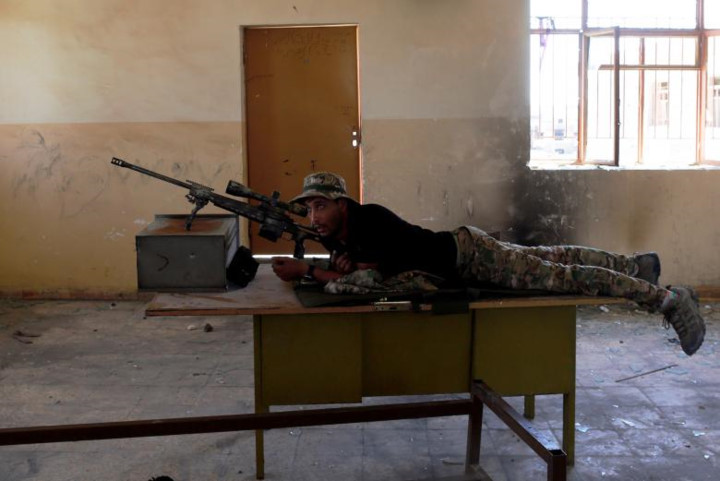 Một lính bắn tỉa của quân đội Iraq nằm trên một chiếc bàn trong một lớp học để ngắm bắn mục tiêu IS.