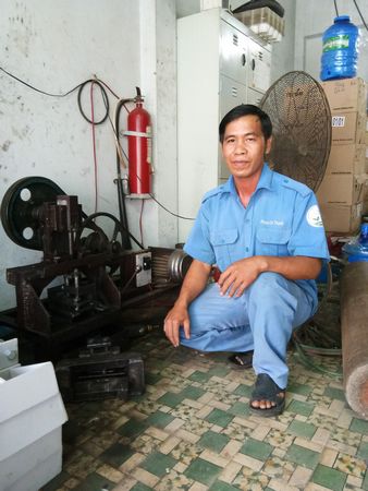 Anh Phạm Chí Thanh bên sáng kiến “Máy đột dập tôn làm hộp bảo vệ đồng hồ nước” của mình.