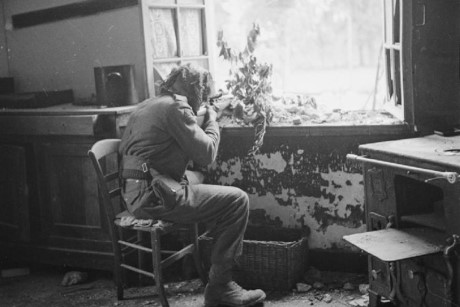 Lính bắn tỉa Anh ngồi tại cửa sổ một ngôi nhà ở Caen theo dõi các lính bắn tỉa của đối phương thông qua kính ngắm viễn vọng.