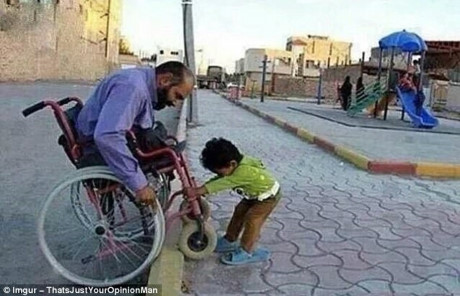 Một đứa trẻ đang cố gắng giúp người đàn ông đi xe lăn vượt qua lề đường.