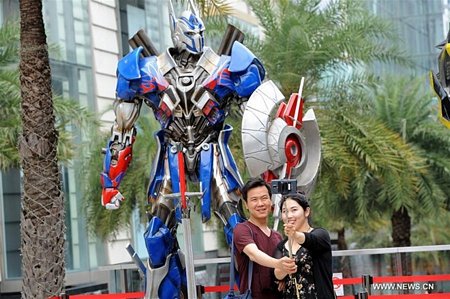 Du khách chụp ảnh với mô hình nhân vật trong phim 'Transformers.' (Nguồn: News.xinhuanet.com)