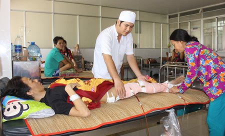 Nhân viên y tế bệnh viện và mẹ bệnh nhân Phước (bà Lê Thị Thủy) chăm sóc phục hồi sau lần phẫu thuật thứ 2 cho anh.