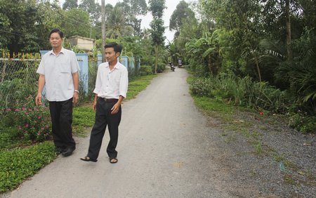 Ông Trần Văn Đúng (trái) đã tích cực vận động người dân kiên cố hóa cống đập và hiến đất xây đường, trụ sở làm việc ấp.