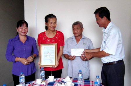 Bà Lê Thị Hồng Đào- Phó Chủ tịch Thường trực Liên đoàn lao động tỉnh (trái) và ông Nguyễn Văn Hồng- Chủ tịch Liên đoàn Lao động TP (phải) trao quyết định bàn giao nhà mới cho gia đình chị Mai.