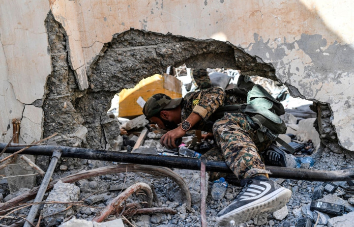 Tay súng SDF nhẹ nhàng chui qua lỗ hổng của một bức tường ở khu vực chiến đấu gần bệnh viện trung tâm Raqqa. Ảnh: AFP.