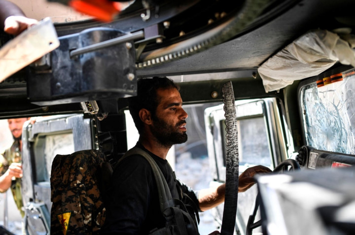 Thành viên SDF ngồi sau vô-lăng của một chiếc xe hư hỏng vì các trận giao tranh ác liệt. Ảnh: AFP.