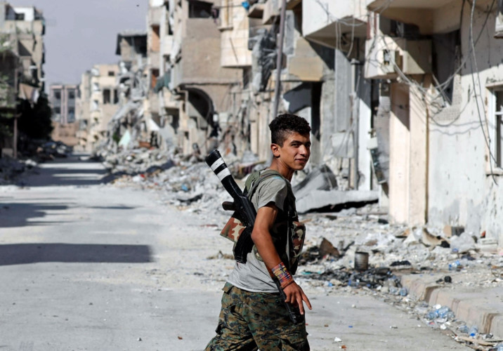 Thành viên trẻ tuổi của SDF đi qua một khu phố đổ nát ở khu phố cổ  của Raqqa. Ảnh: Reuters.