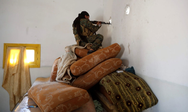 Tay súng của SDF nã đạn qua một lỗ thủng trên tường. Ảnh: Reuters.