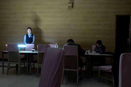 Một nữ phục vụ bàn đặt một đèn ắc quy trên bàn khi mất điện ở Chongjin vào tháng 4/2015.