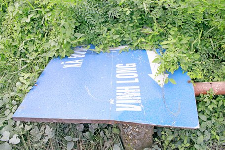 Biển báo hướng dẫn đường ngã ba Đồng Phú- Vĩnh Long- Bến Tre nằm rạp dưới bãi cỏ từ rất lâu.