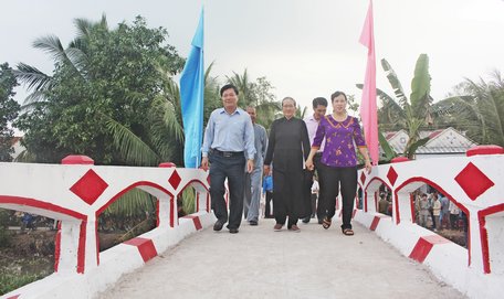 Ông Lê Văn Phúc- Chủ tịch UBND huyện Bình Tân (bìa trái)-cùng người dân qua cầu sau lễ khánh thành. 