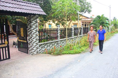 Bà Nguyễn Thị Hồng Nhung (đi bên trái) tự hào về con đường nông thôn mới có cổng rào, bờ hoa trước nhà.