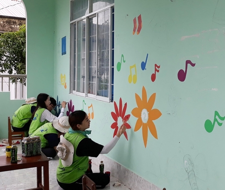 Các tình nguyện viên sơn vẽ bức tường tại Trường Mẫu giáo Trung An.