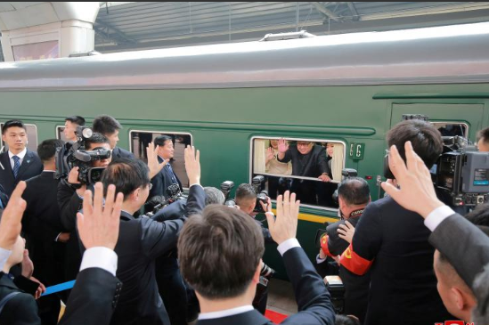 Nhà lãnh đạo Triều Tiên cùng vợ vẫy tay chào các phóng viên từ tàu hỏa. Ảnh: Reuters