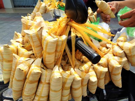 Những chiếc bánh lá dừa thon dài, với màu vàng bắt mắt được treo đầy cổ xe.